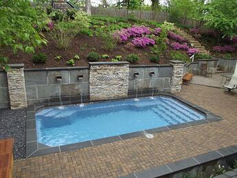 inground fiberglass pool with retaining wall and water features