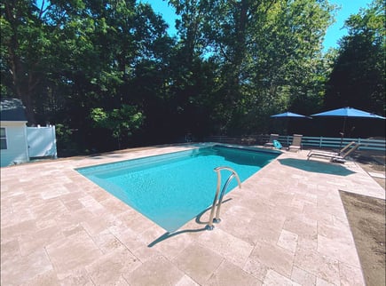 Travertine installed around a River Pools R32 inground fiberglass pool. 