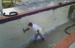 Builder troweling the plaster to a smooth finish in a concrete pool