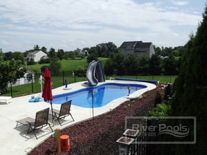 freeform fiberglass pool with deck chairs and slide