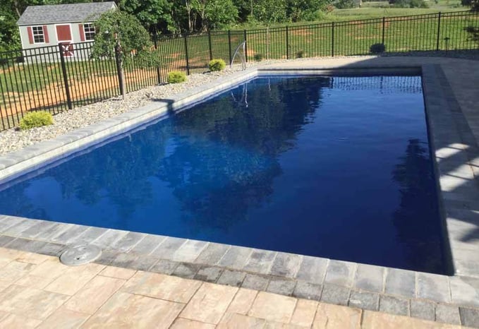 blue dark bottom fiberglass pool with fence