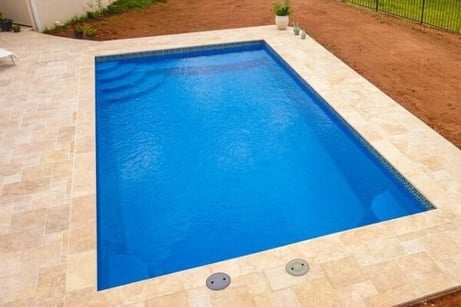 inground fiberglass pool with waterline tile and pavers