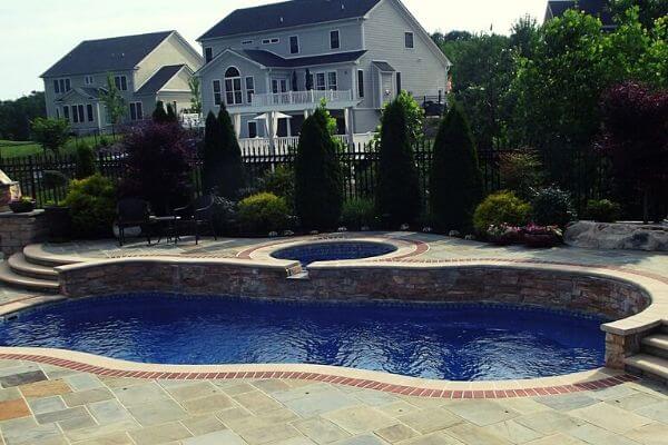 swimming pool with spa and elevated patio