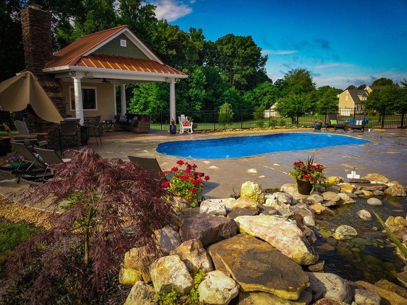 Blue freeform pool surrounded by plants and other landscaping.