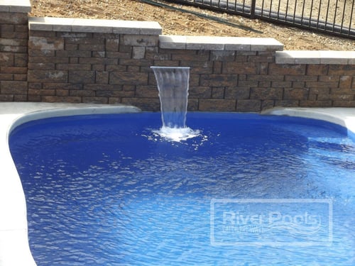 retaining wall with water cascade into freeform fiberglass pool