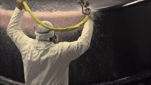 Manufacturer spraying chopped fiberglass onto fiberglass pool