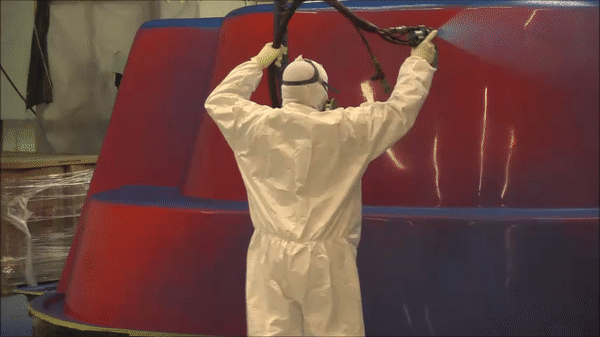 Manufacturer spraying the gelcoat onto fiberglass pool