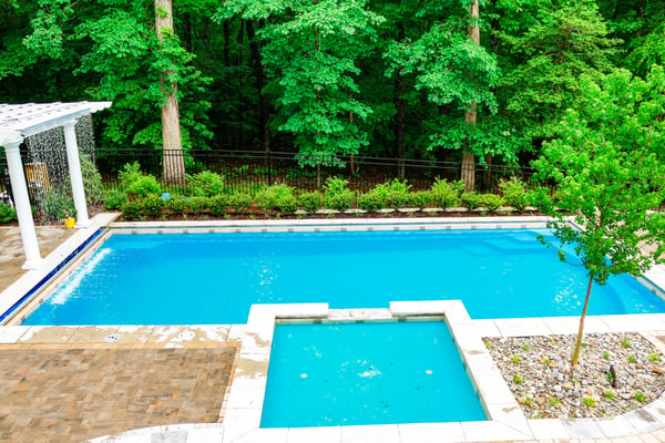 G36 fiberglass pool with elevated tanning ledge and green landscaping