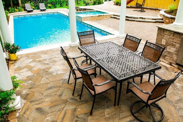 G36 fiberglass pool with elevated tanning ledge, pergola, stone patio, and table with chairs