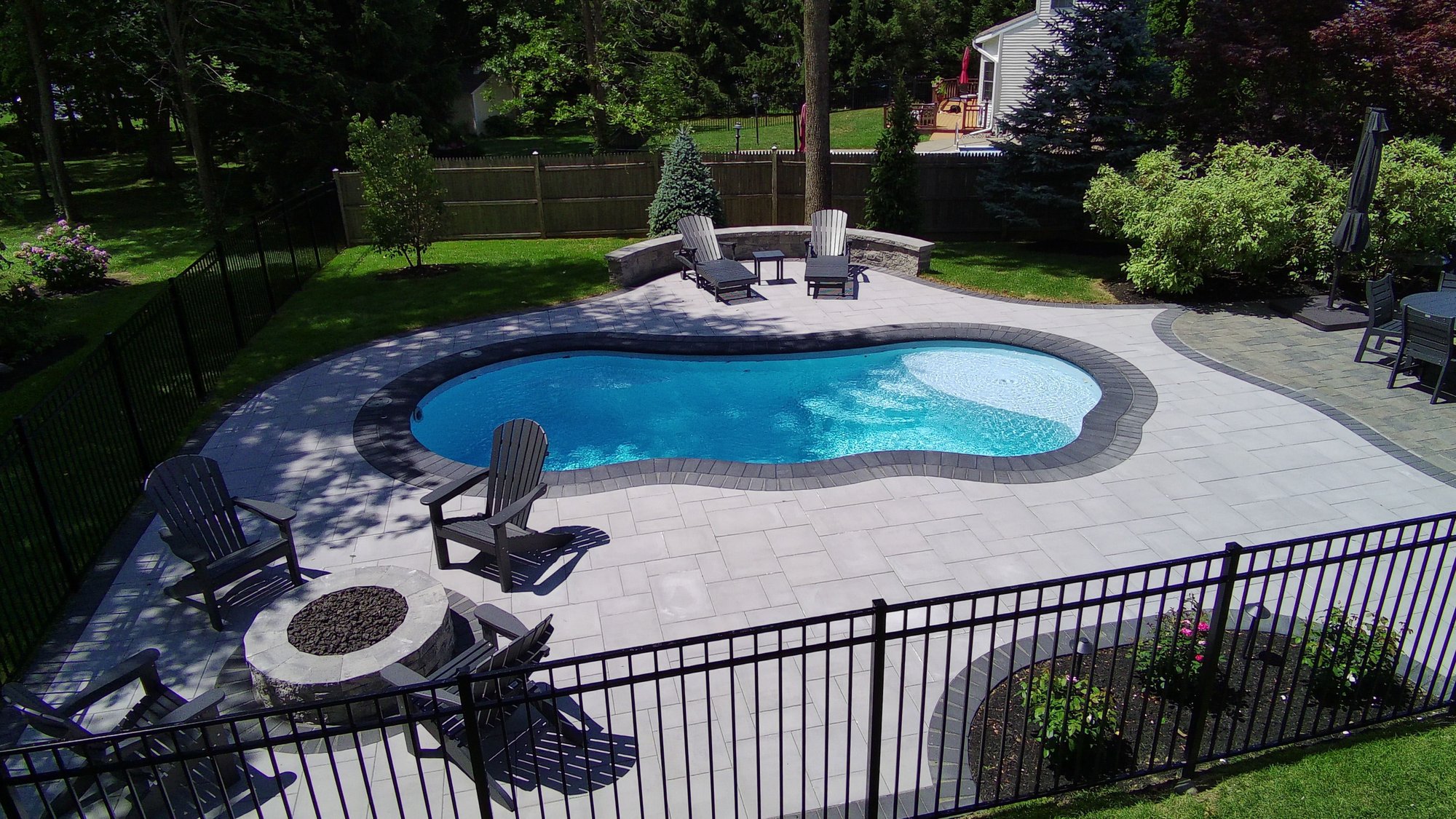 Kid-friendly fiberglass pool with fire pit and seating area in a landscaped backyard in Schenectady, NY