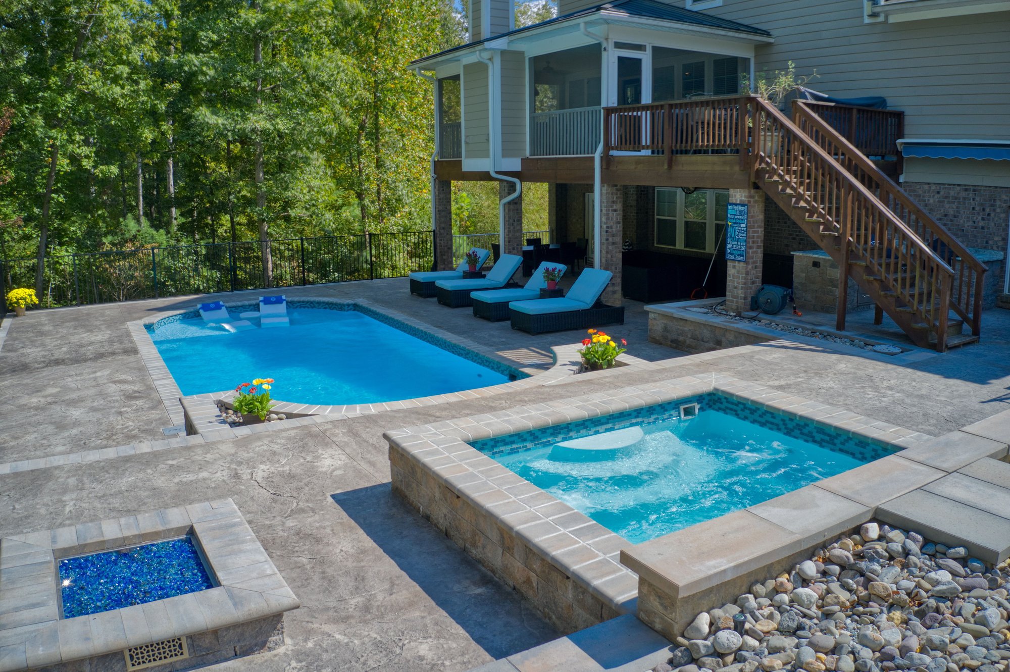 Fiberglass inground pool installation in Bentonville, AR, with custom spa, stamped concrete patio, and wooded backyard.