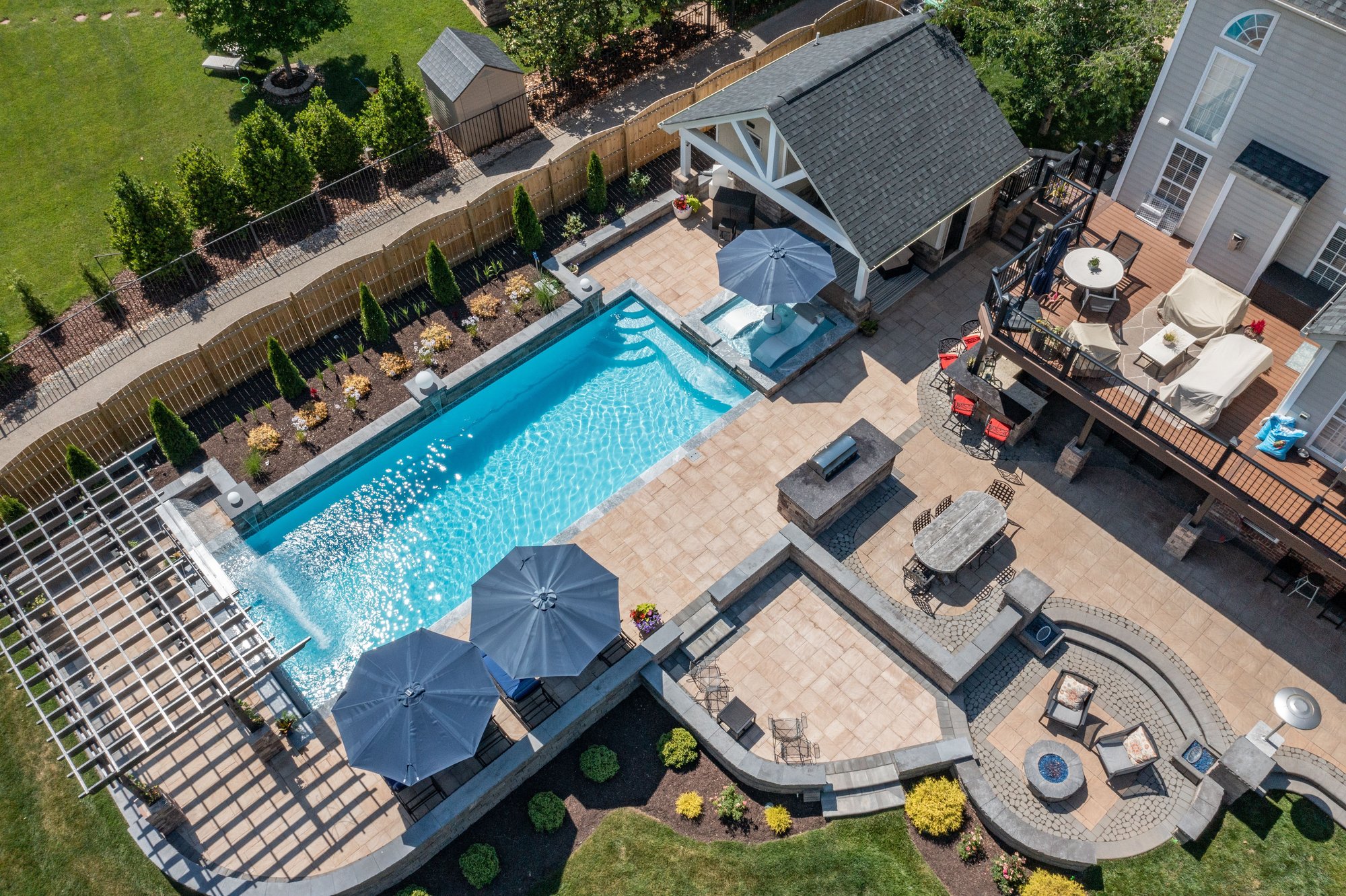 Aerial view of fiberglass inground pool installation in Branson, MO, with tanning ledge, pergola, paver patio, and outdoor kitchen.