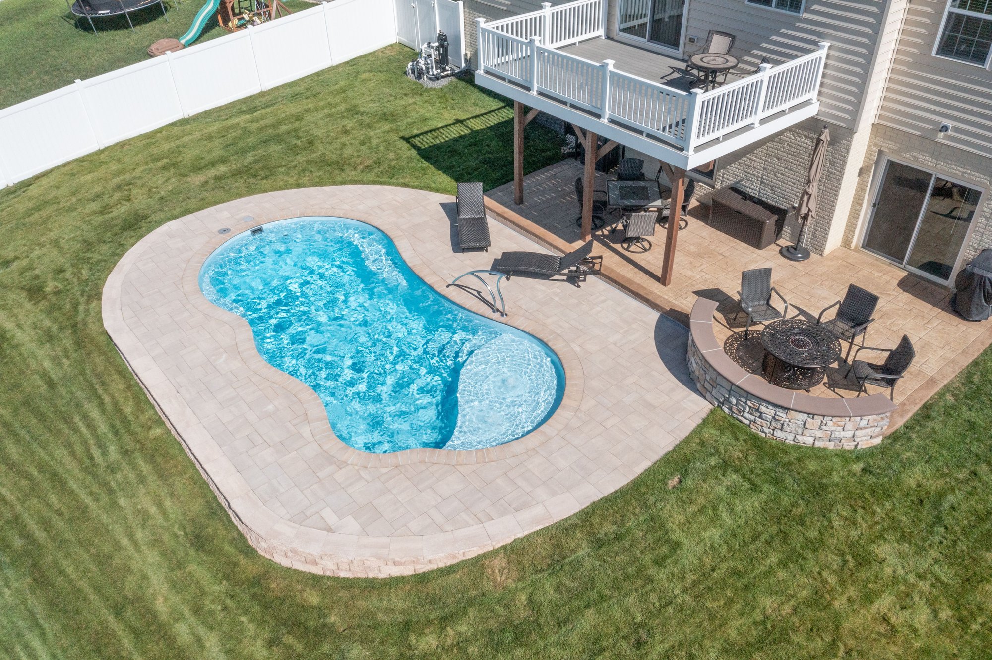 Fiberglass inground pool installation in Springdale, AR, with paver patio, raised deck, fire pit, and family-friendly backyard.