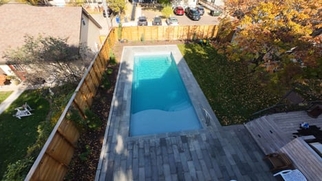 Fiberglass pool installed by River Pools Red Wing in a small backyard during fall, surrounded by autumn leaves and modern stone patio.