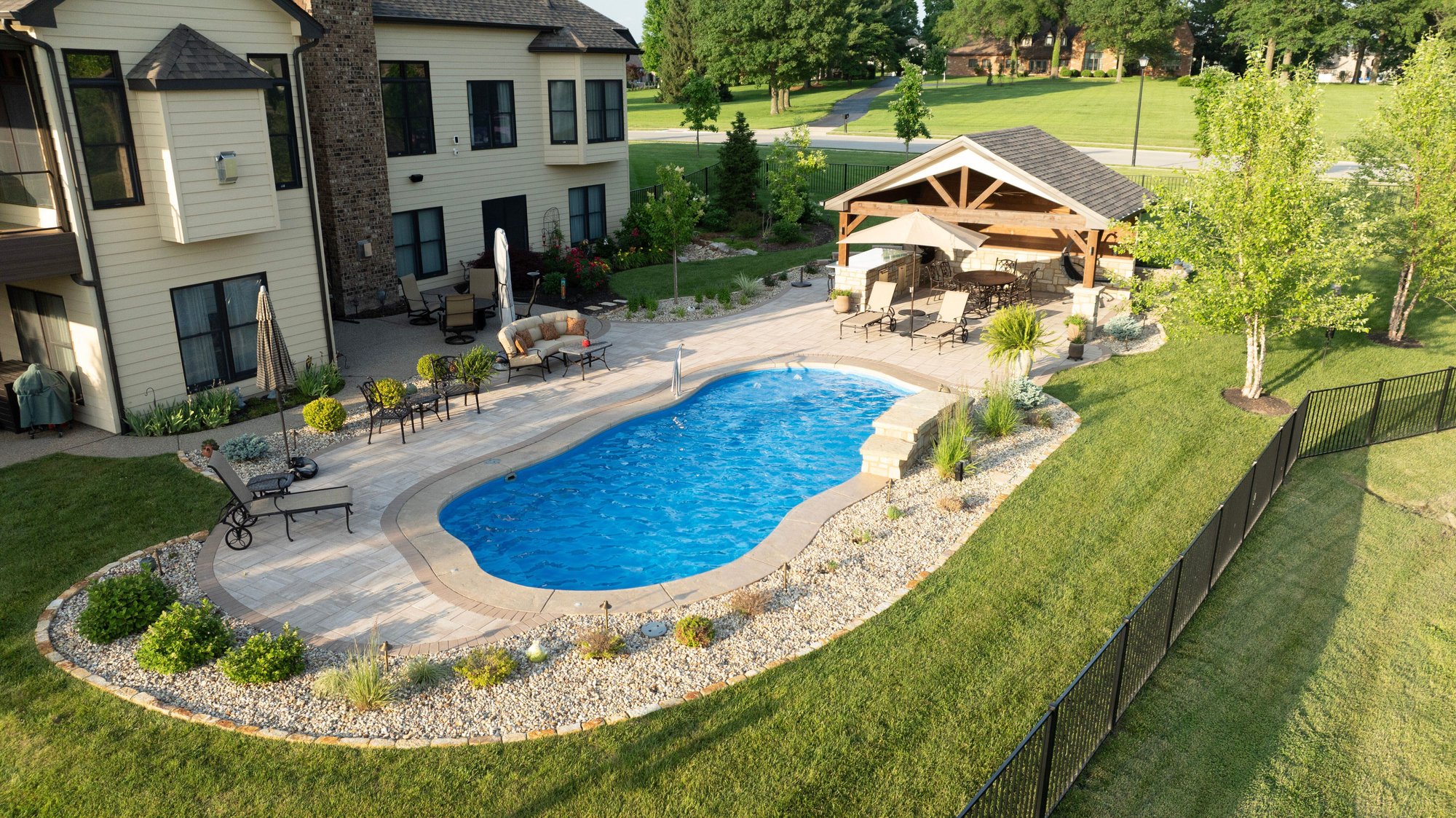 Backyard fiberglass pool installed in O'Fallon, MO with sun ledge, seating area, and surrounding string lights by River Pools St. Louis.