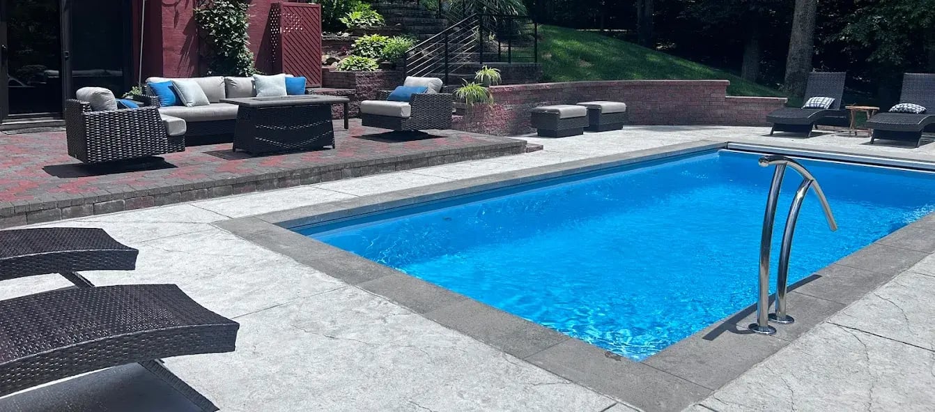 Inground fiberglass pool with textured concrete deck in Chesapeake.