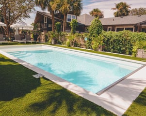 Fiberglass pool installed by River Pools Savannah with artificial turf, lounge chairs, and tropical landscaping in a coastal backyard.