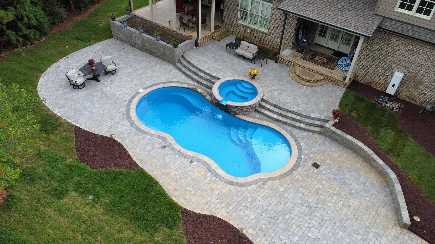Fiberglass pool with integrated spa and paver patio installed in Greensboro, NC by River Pools of the Triad.