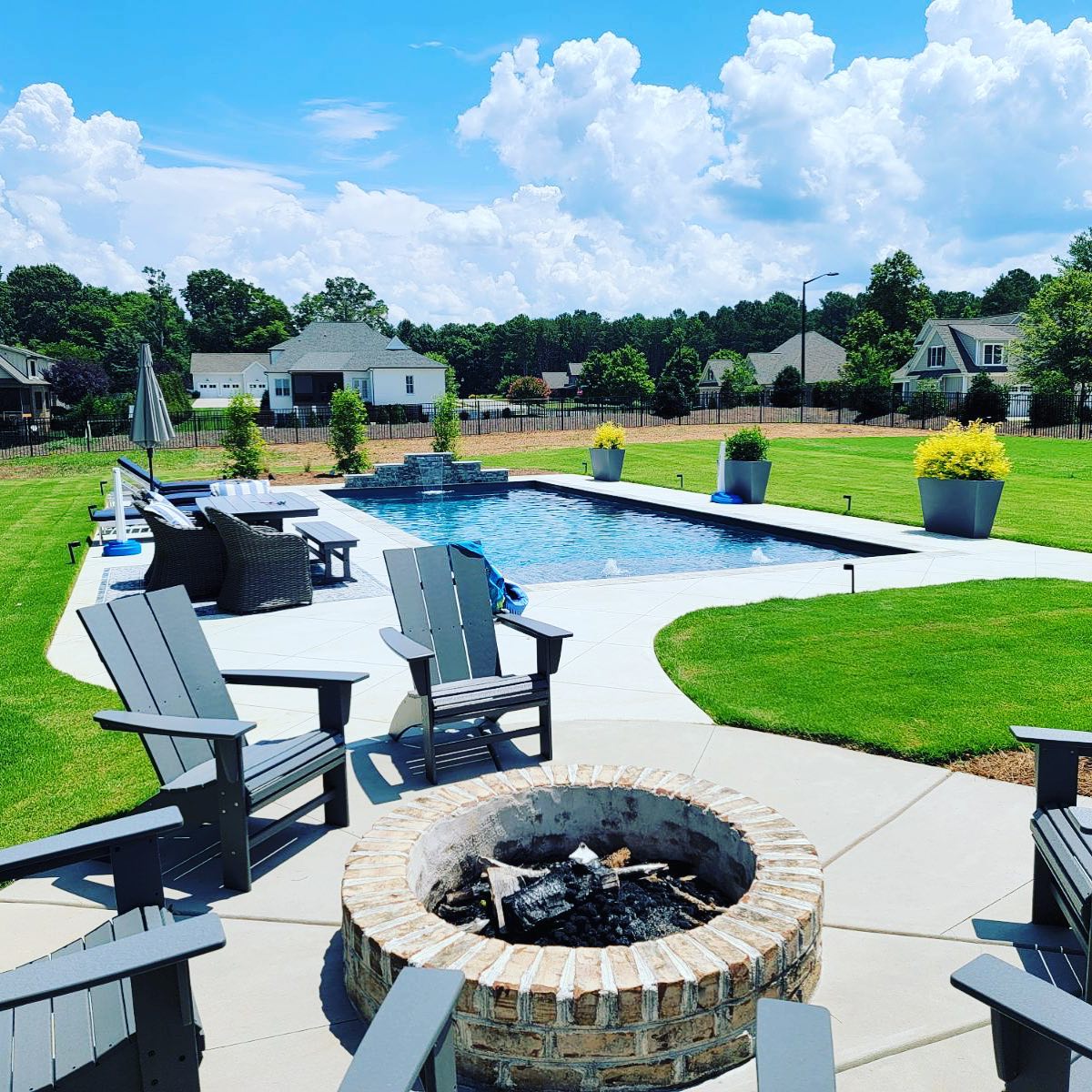 Backyard fiberglass pool with fire pit and lounge seating installed by River Pools of the Triad, serving towns across the Piedmont and Triad regions of North Carolina.