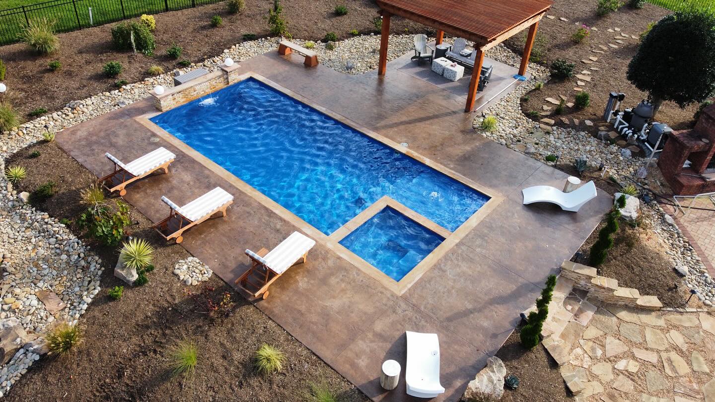 Modern fiberglass pool and lounge area with pergola installed in a Winston-Salem, NC backyard.