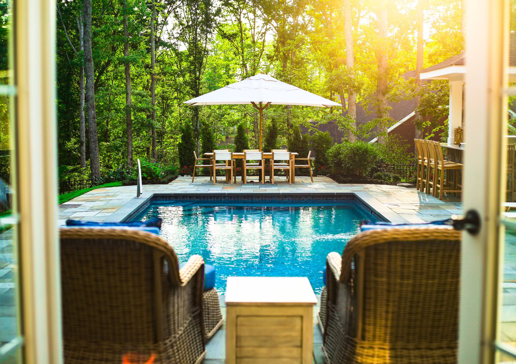 View of the River Pools T40 fiberglass pool and dining area from beneath a covered patio.