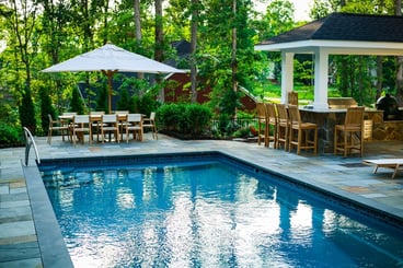 T40 pool model with stone patio, outdoor kitchen, and dining area