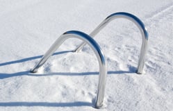Pool ladder emerging from snow-covered fiberglass pool during winter, illustrating cold-climate durability.