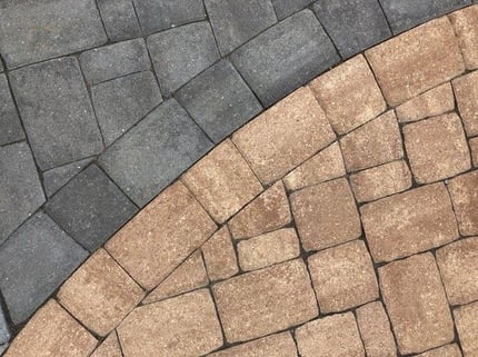 Concrete pavers with contrasting colors to create defined spaces around an inground pool.