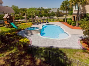 River Pools C40 + RS08 with spillway in Caribbean Sparkle with concrete paver patio and natural stone coping