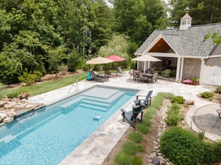 River Pools M35 in Diamond color with a cascade, natural stone patio, and concrete paver coping