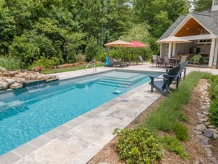River Pools M35 in Diamond color with a cascade, natural stone patio, and concrete paver coping