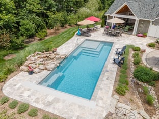 River Pools M35 in Diamond color with a cascade, natural stone patio, and concrete paver coping