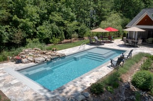 River Pools M35 in Diamond color with a cascade, natural stone patio, and concrete paver coping