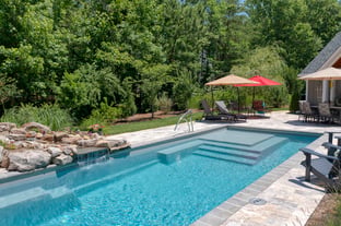 River Pools M35 in Diamond color with a cascade, natural stone patio, and concrete paver coping