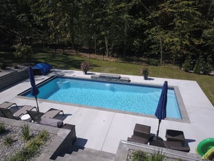 R32 pool in Caribbean with paver coping and brushed concrete decking featuring a cascade water feature