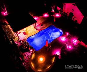 O30 fiberglass pool with pink patio lights after dark