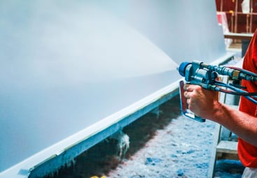 applying gelcoat finish to a fiberglass pool shell during factory manufacturing process.