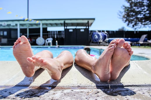 People lounging by the pool with their feet closest to the camera.