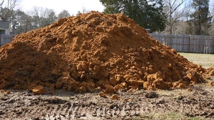 a big pile of dirt/clay, excavated for a fiberglass pool installation