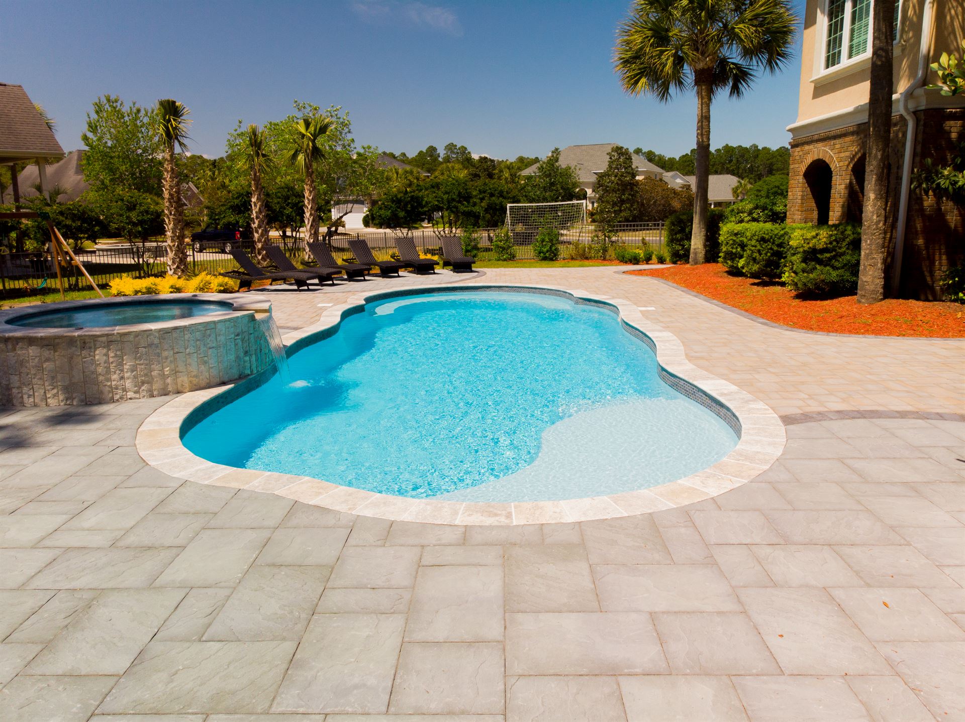 River Pools C40 + RS08 with spillway in Caribbean Sparkle with concrete paver patio and natural stone coping