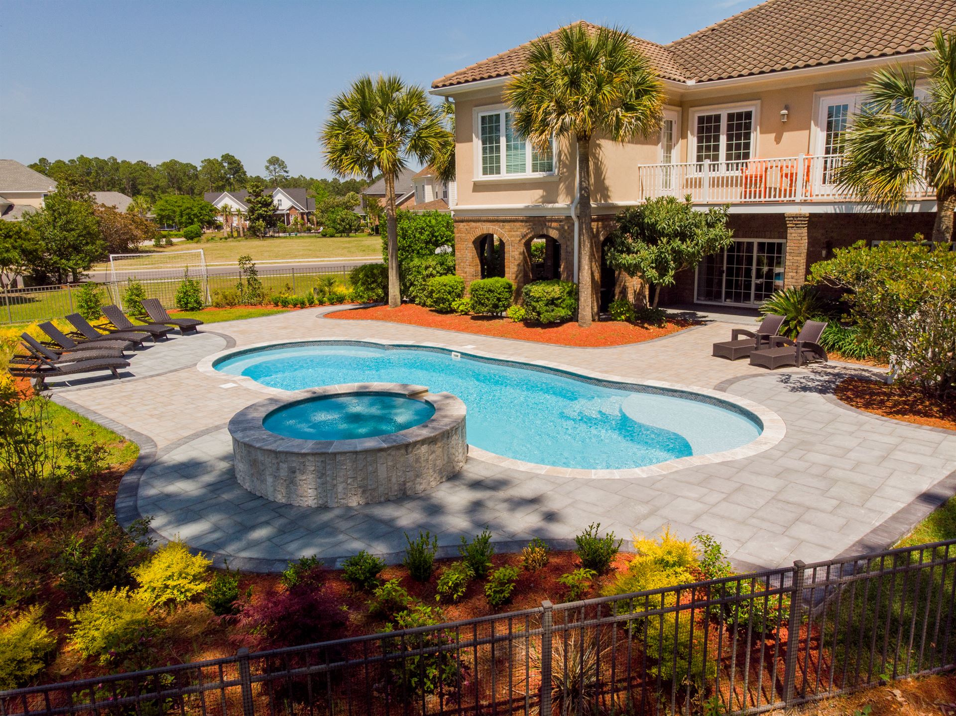 River Pools C40 + RS08 with spillway in Caribbean Sparkle with concrete paver patio and natural stone coping