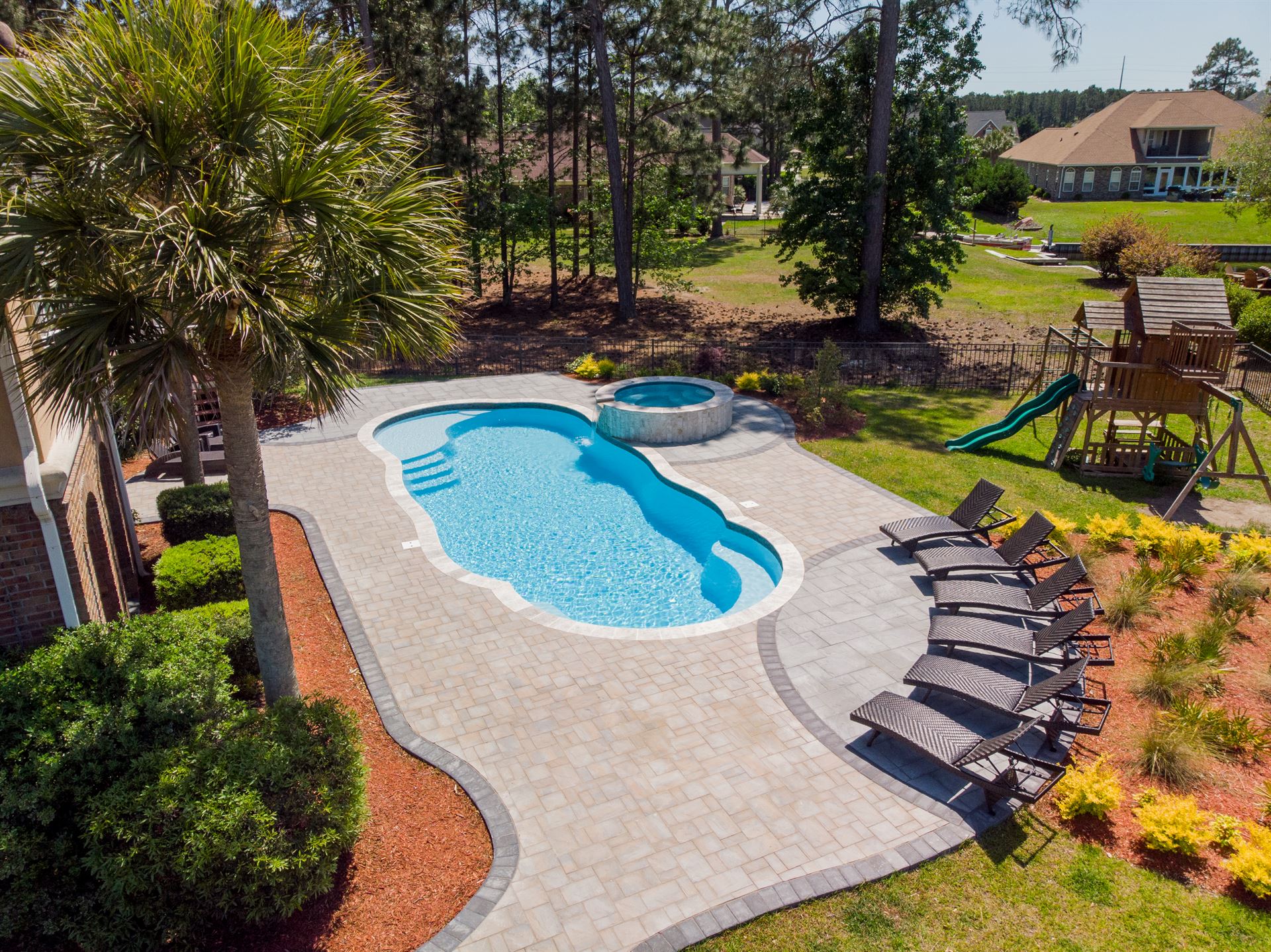 River Pools C40 + RS08 with spillway in Caribbean Sparkle with concrete paver patio and natural stone coping