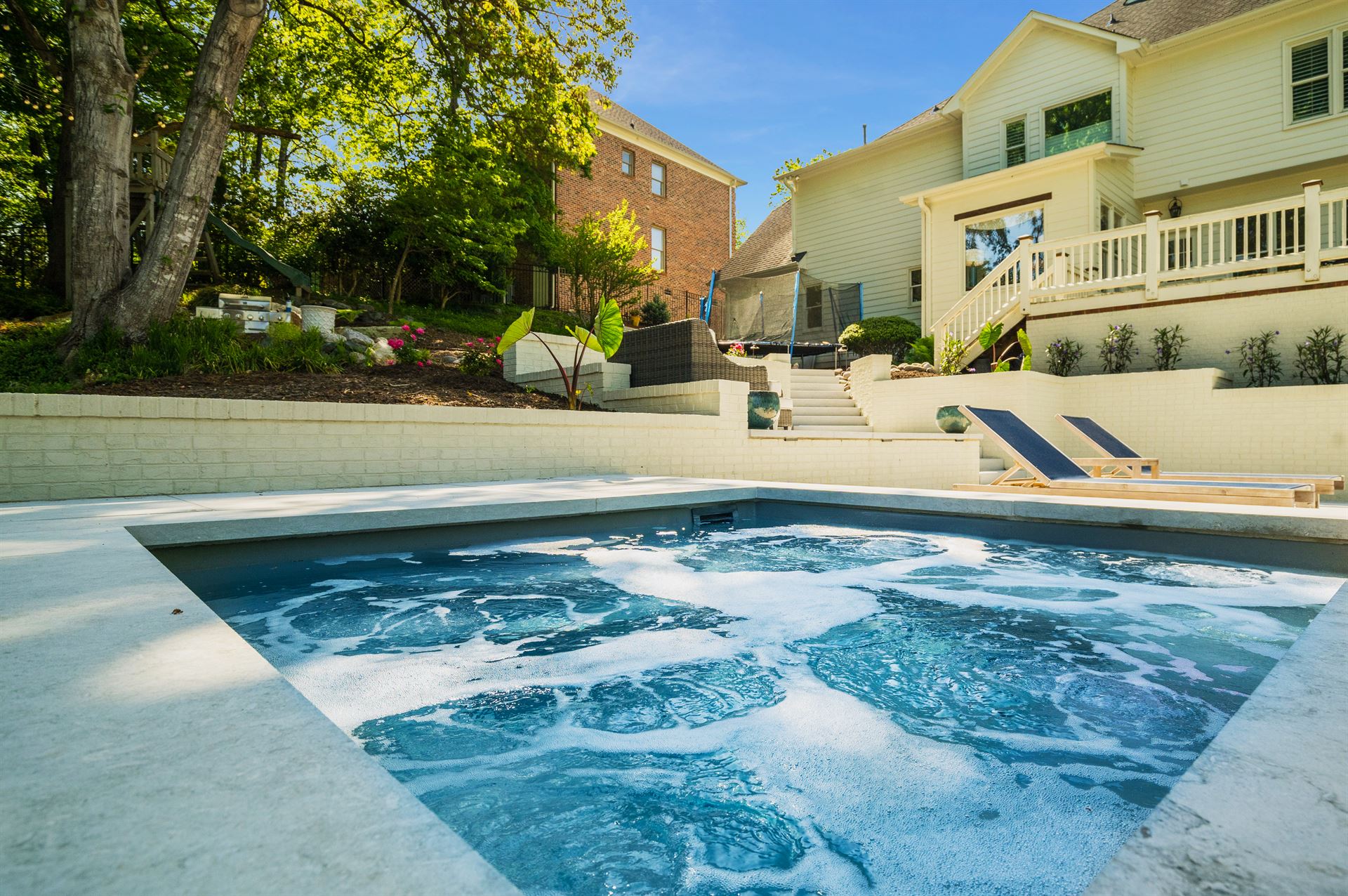 River Pools D40 + SS08 in Diamond with cascades, bubblers, and natural stone patio and coping