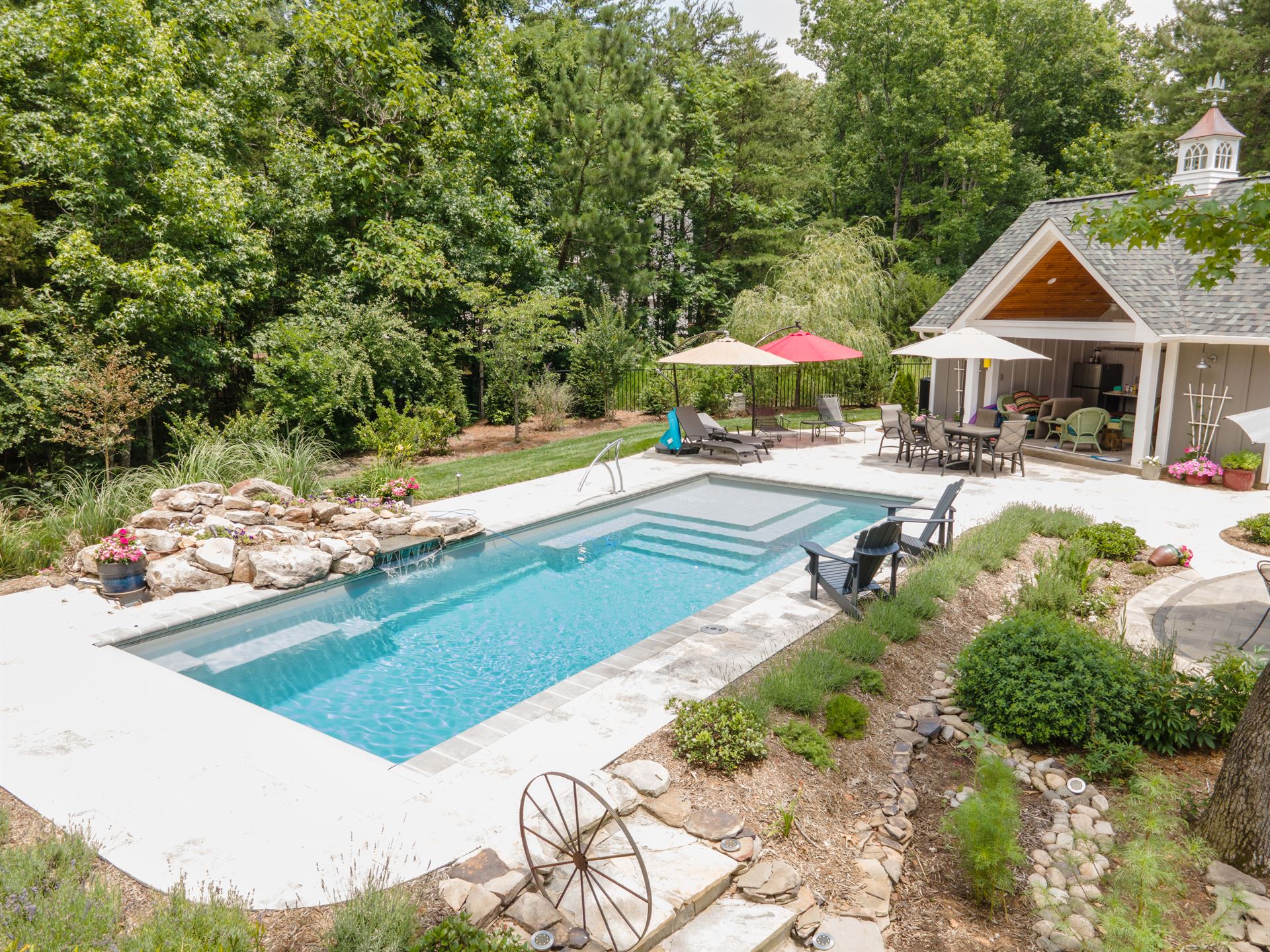 River Pools M35 in Diamond color with a cascade, natural stone patio, and concrete paver coping