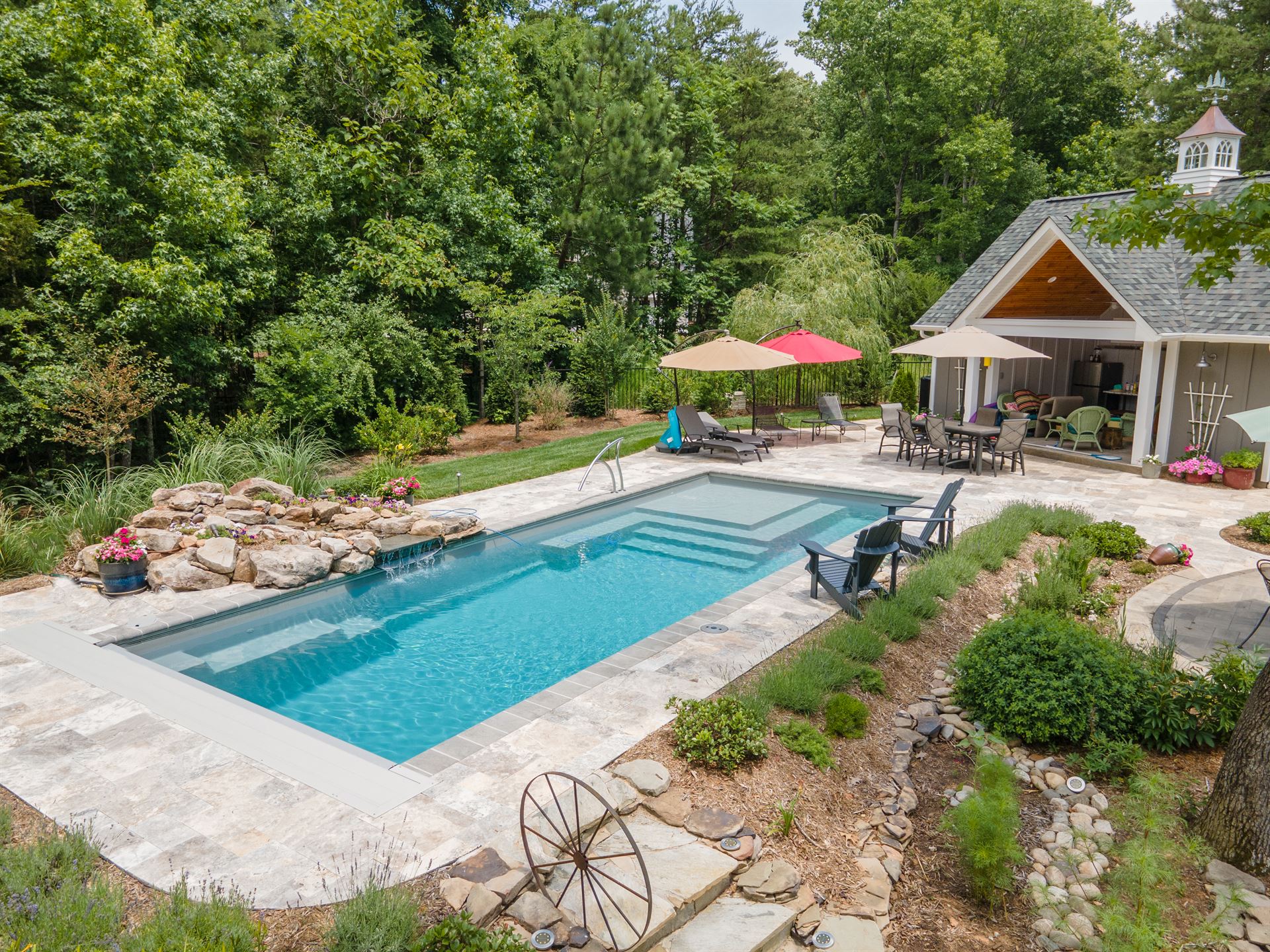 River Pools M35 in Diamond color with a cascade, natural stone patio, and concrete paver coping