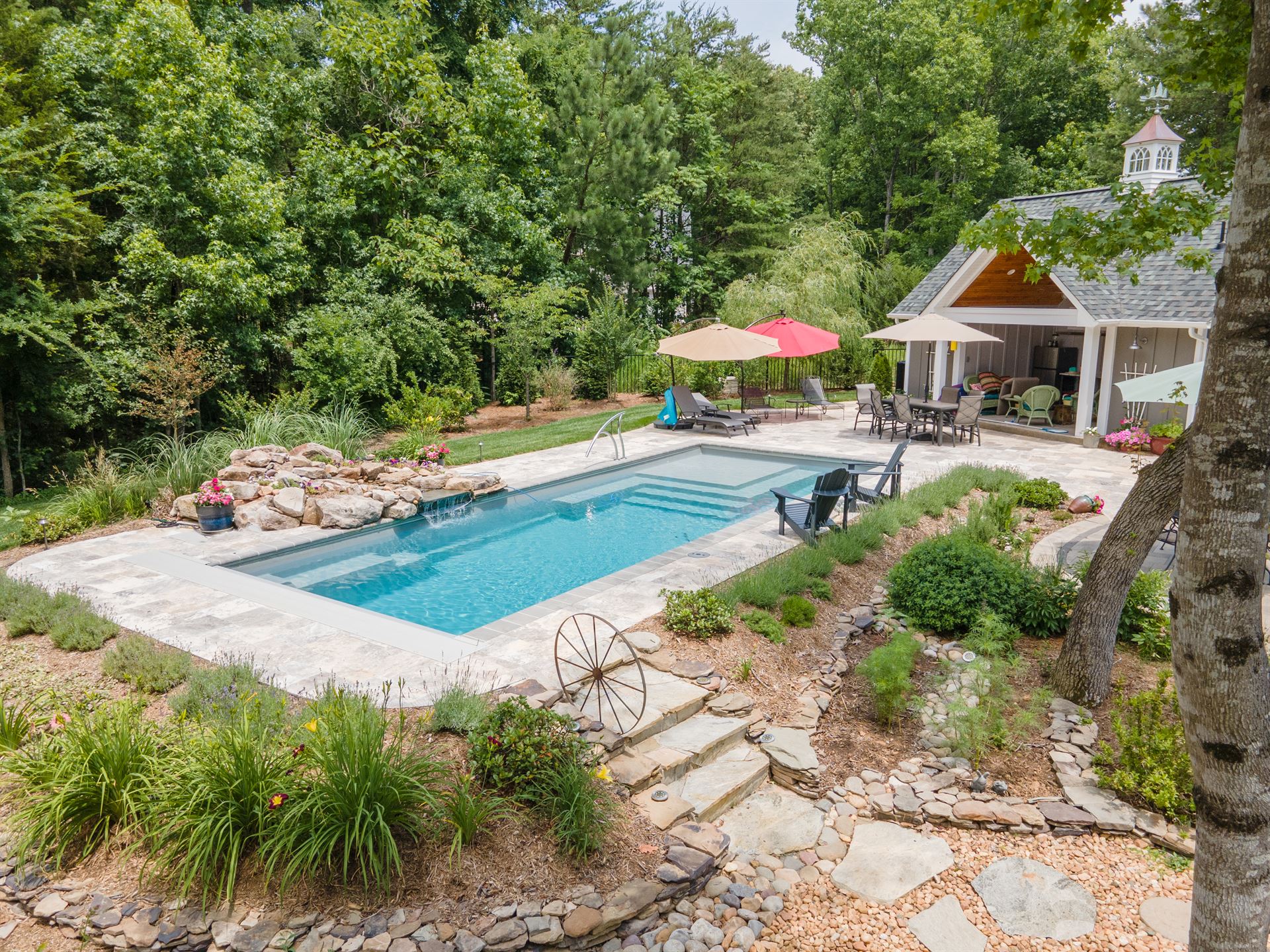 River Pools M35 in Diamond color with a cascade, natural stone patio, and concrete paver coping