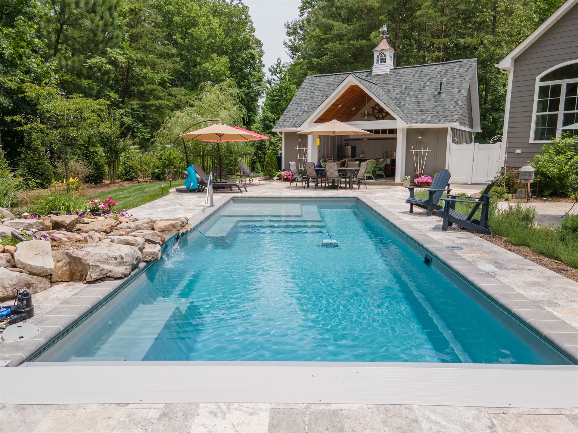 River Pools M35 in Diamond color with a cascade, natural stone patio, and concrete paver coping