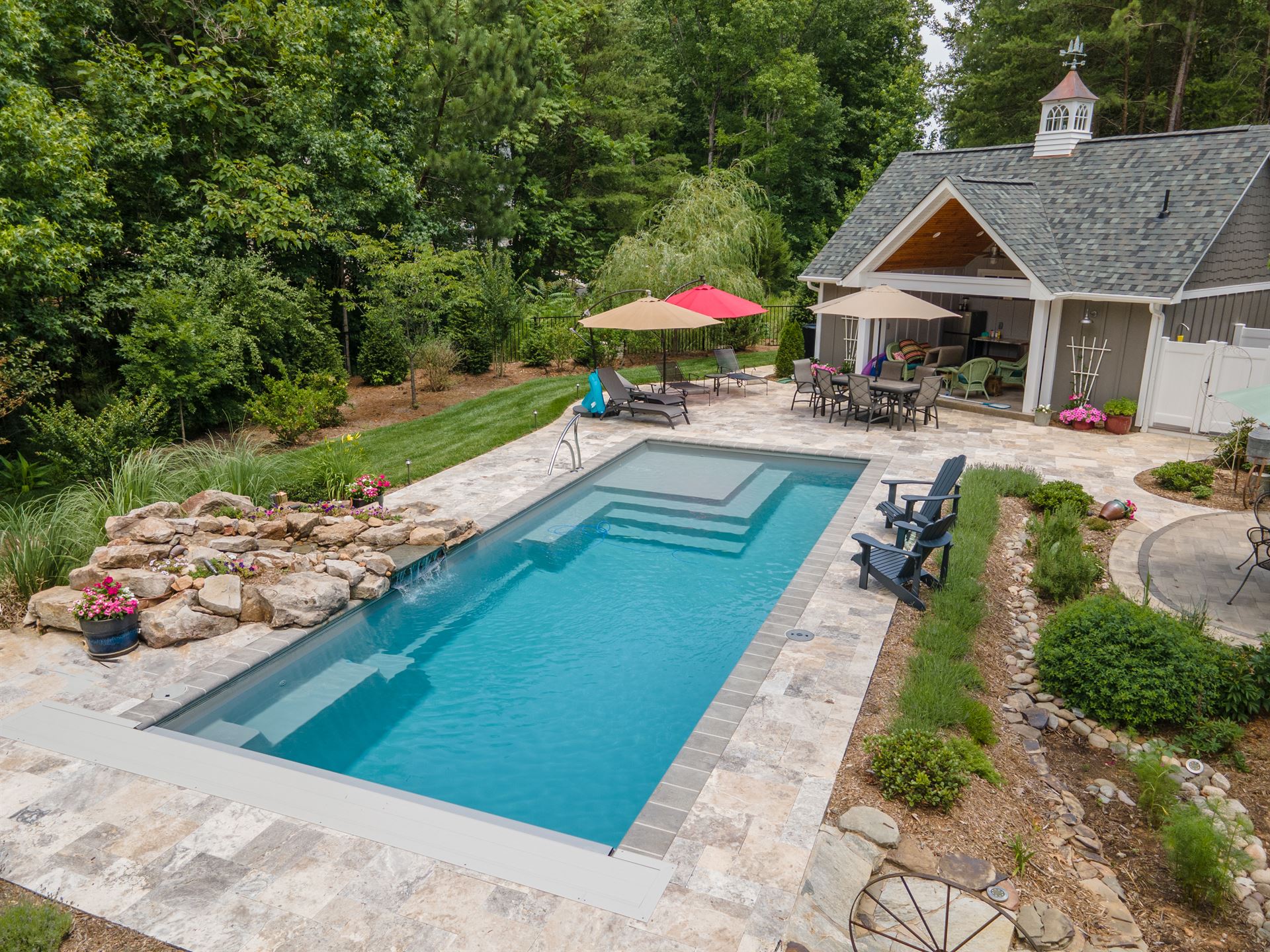 River Pools M35 in Diamond color with a cascade, natural stone patio, and concrete paver coping