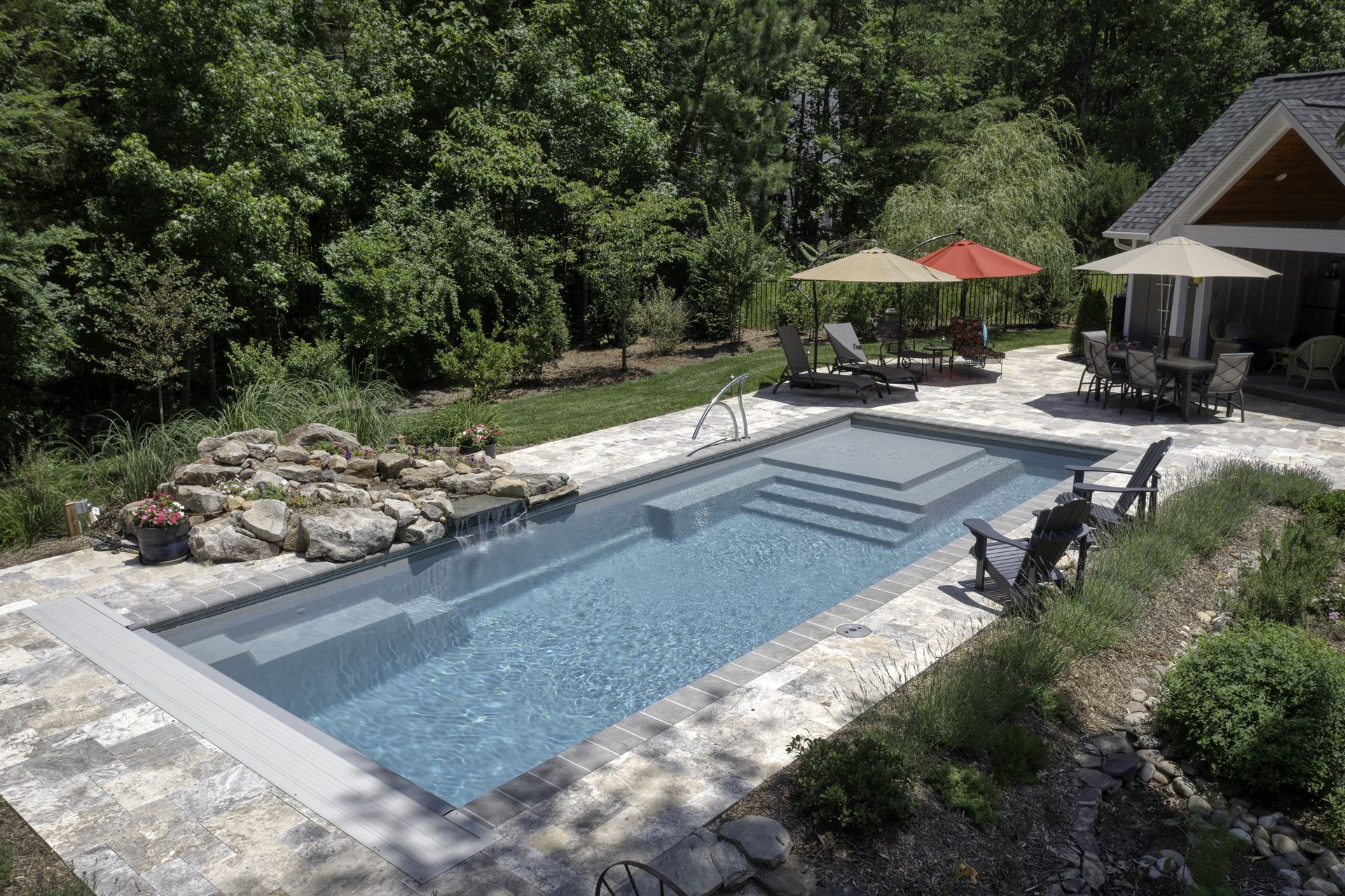 River Pools M35 in Diamond color with a cascade, natural stone patio, and concrete paver coping