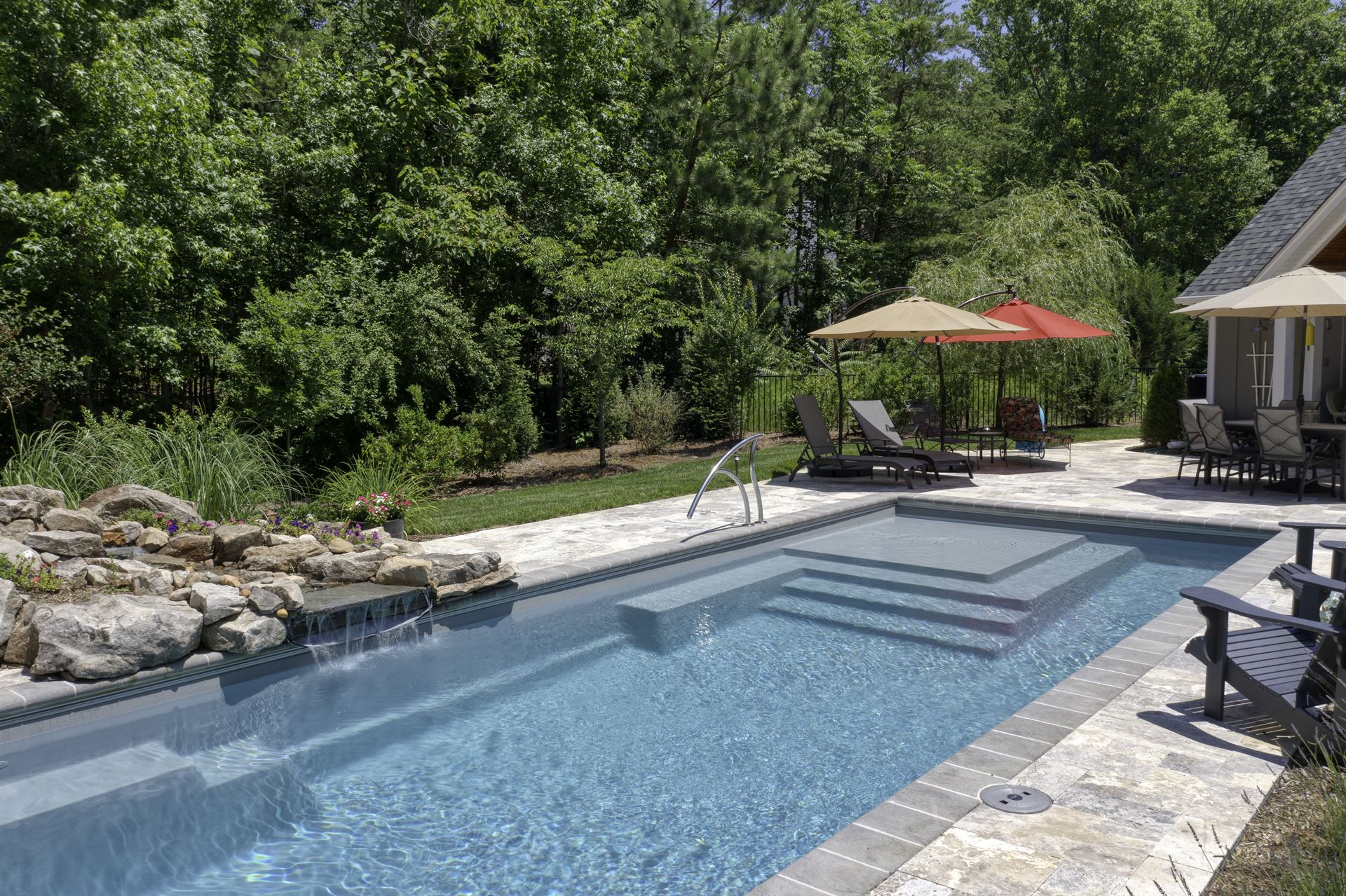 River Pools M35 in Granite Gray with a cascade, natural stone patio, and concrete paver coping